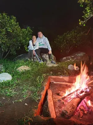 a man and a woman sitting next to a fire at Pradera Ecoliving in Betania