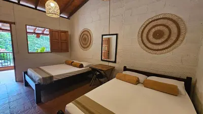a room with two beds and a table in it at Pradera Ecoliving in Betania