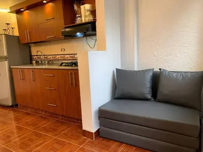 a living room with a couch and a kitchen at Acogedor Apartamento Urbanización Tricentenario in Medellín