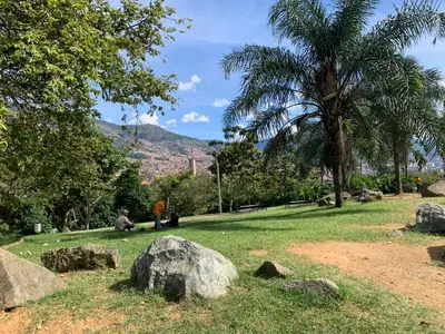 two people sitting on the grass in a park with rocks at Acogedor Apartamento Urbanización Tricentenario in Medellín