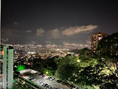 a city at night with cars parked in a parking lot at Medellin parque lleras poblado palmas in Medellín
