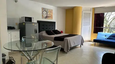 a living room with a bed and a glass table at Apartaestudio Cerca a los Molinos in Medellín