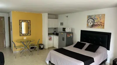 a bedroom with a bed and a table and a kitchen at Apartaestudio Cerca a los Molinos in Medellín