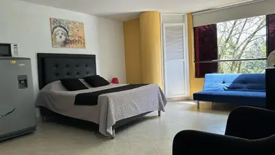 a bedroom with a bed and a blue couch at Apartaestudio Cerca a los Molinos in Medellín