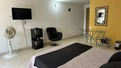 a bedroom with a bed and a television and a chair at Apartaestudio Cerca a los Molinos in Medellín