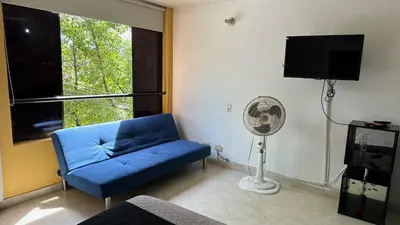 a living room with a blue couch and a fan at Apartaestudio Cerca a los Molinos in Medellín