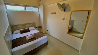 a small bedroom with a bed and a mirror at Hotel Buenos Aires Central in Medellín