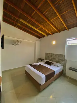 a bedroom with a large bed with a wooden ceiling at Hotel Buenos Aires Central in Medellín
