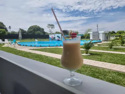 a drink sitting on a ledge next to a pool at Hotel nelumbo in Mariquita
