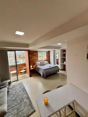 a bedroom with a bed and a living room at Increíble Apartaestudio Cerca al Centro Comercial Los Molinos in Medellín