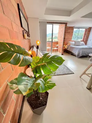 a living room with a plant and a brick wall at Increíble Apartaestudio Cerca al Centro Comercial Los Molinos in Medellín