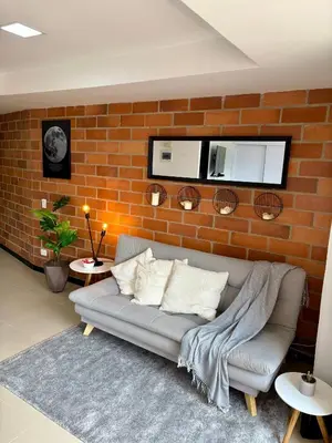 a living room with a couch against a brick wall at Increíble Apartaestudio Cerca al Centro Comercial Los Molinos in Medellín