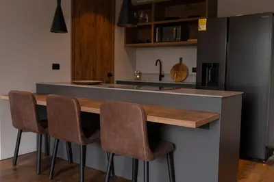 a kitchen with a counter with chairs and a refrigerator at Kiin Living- 