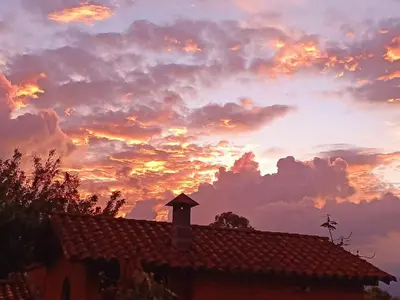 a sunset behind a roof of a house at Casa Campestre con terraza para 10 Poblado S Lucas 108 in Medellín