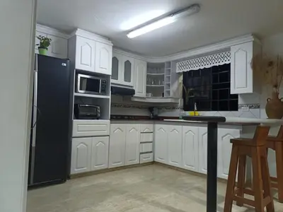 a kitchen with white cabinets and a black refrigerator at Casa Campestre con terraza para 10 Poblado S Lucas 108 in Medellín