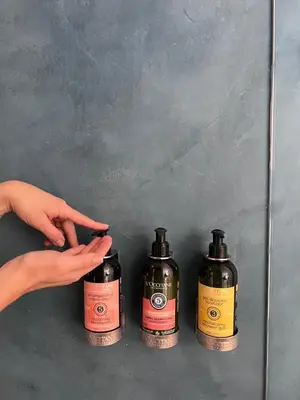 three bottles of liquid sitting on a counter with a hand at Del Trópico Hotel By GyC Hotels in Sopetran