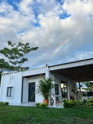 a white house with a rainbow in the sky at Cabaña Campestre con Piscina en la Hacienda Nápoles in Doradal