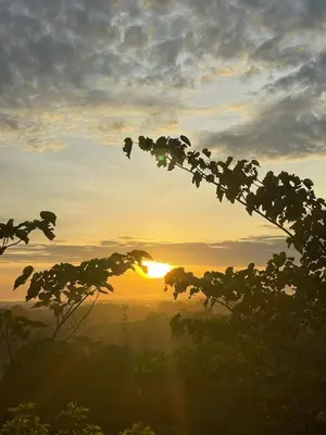 a sunset with the sun setting in the background at Cabaña Campestre con Piscina en la Hacienda Nápoles in Doradal
