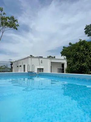 a large swimming pool in front of a white building at Cabaña Campestre con Piscina en la Hacienda Nápoles in Doradal