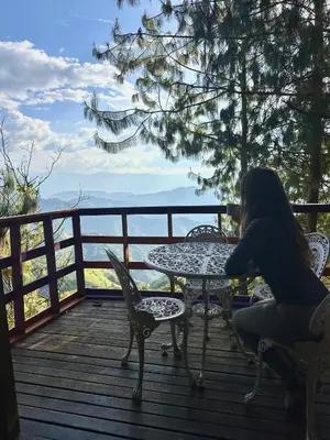 a woman sitting at a table on a deck at LA CASA EN EL AIRE - Abejorral in Abejorral