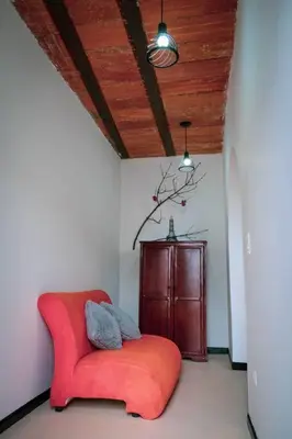 a red chair in a room with a wooden ceiling at Amplio duplex con terraza privada. in Medellín