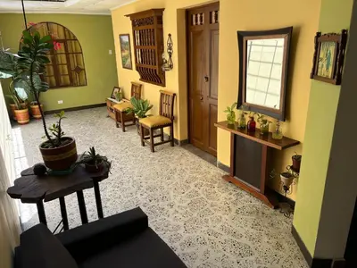 a living room with a couch and a table and chairs at Casa Grande Hostal in Medellín