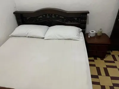 a bed with two white pillows and a wooden headboard at Casa Grande Hostal in Medellín