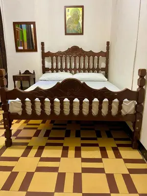 a large wooden bed in a room with a checkered floor at Casa Grande Hostal in Medellín