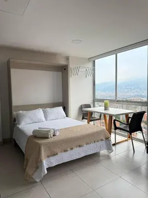 a bedroom with a bed and a table and a view at Apto Familiar in poblado in Medellín