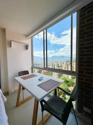 a table and chairs in a room with a large window at Apto Familiar in poblado in Medellín