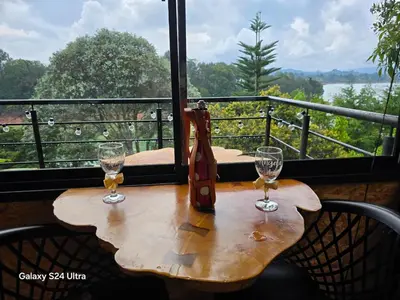a wooden table with two wine glasses on a balcony at Refugio del Lago in Guatapé