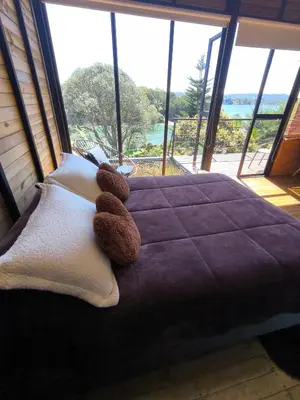 a teddy bear sitting on a bed in a bedroom at Refugio del Lago in Guatapé