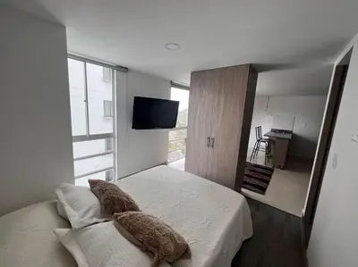 a bedroom with a bed with two pillows and a television at Cómodo apartaestudio in Manizales