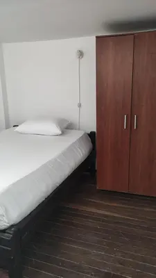 a bedroom with a bed and a wooden cabinet at Habitación sencilla y central #6 in Medellín