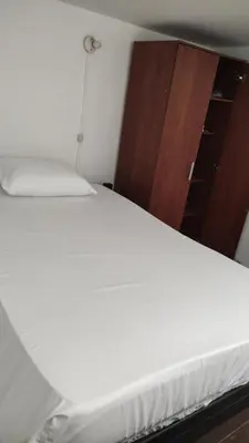 a white bed in a bedroom with a wooden cabinet at Habitación sencilla y central #6 in Medellín