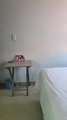 a small wooden table with a box on it next to a bed at Habitación en apartamento compartido en Envigado in Envigado