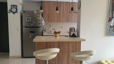 a kitchen with a counter with two chairs and a refrigerator at Habitación en apartamento compartido en Envigado in Envigado
