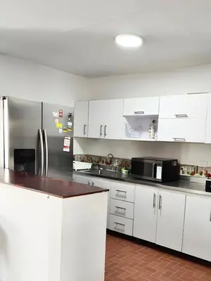 a kitchen with white cabinets and a stainless steel refrigerator at CASA ESTADIO MEDELLIN Amplio Apartamento Renovado para Familias, Grupos o Delegaciones Deportivas cerca al Estadio Atanasio Girardot - Laureles-Estadio in Medellín