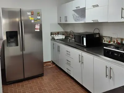 a kitchen with a stainless steel refrigerator and white cabinets at CASA ESTADIO MEDELLIN Amplio Apartamento Renovado para Familias, Grupos o Delegaciones Deportivas cerca al Estadio Atanasio Girardot - Laureles-Estadio in Medellín