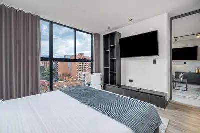 a bedroom with a large bed and a large window at Apartamentos HOUSY Laureles in Medellín
