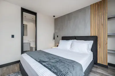 a bedroom with a large bed with white sheets at Apartamentos HOUSY Laureles in Medellín