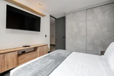 a bedroom with a large bed and a flat screen tv at Apartamentos HOUSY Laureles in Medellín