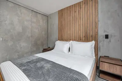 a bedroom with a white bed with a wooden headboard at Apartamentos HOUSY Laureles in Medellín