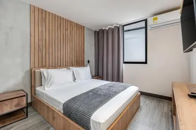 a bedroom with a large bed and a television at Apartamentos HOUSY Laureles in Medellín