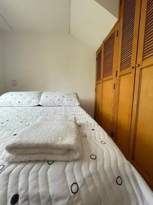 a bedroom with a white bed with a wooden cabinet at Ideal para grupos y nómadas Apto 2 hab amplio in Sabaneta