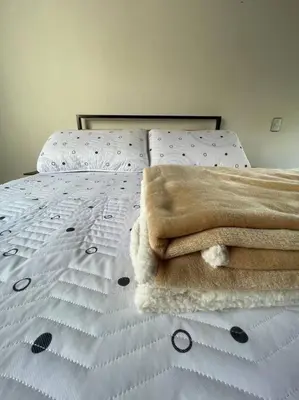 a bed with a blanket on top of it at Ideal para grupos y nómadas Apto 2 hab amplio in Sabaneta