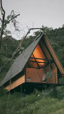 a small house with a pitched roof in a field at Ecolodge Cuentos de Agua in Villamaría