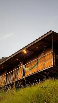 a large wooden building with a porch on a field at Ecolodge Cuentos de Agua in Villamaría