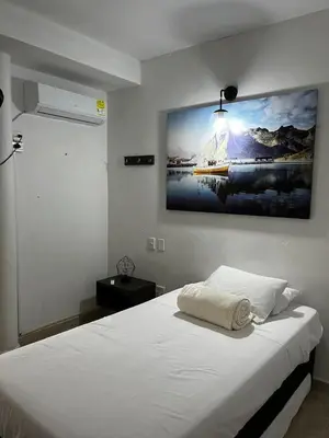 a bedroom with a white bed with a painting on the wall at Villa Athenea-Santorini Colombiano in Puerto Triunfo