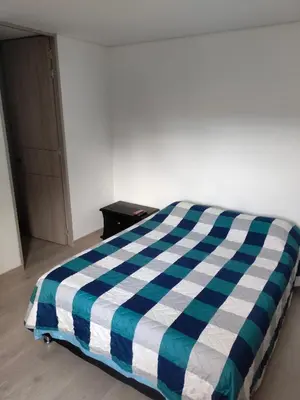 a bed with a blue and white checkered blanket at Apartamento Sabaneta Antioquía in Sabaneta